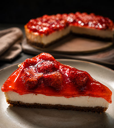 Ambachtelijke aardbeien cheesecake met romige cheesecakevulling, frisse aardbeientopping en een luxe handgemaakte uitstraling.