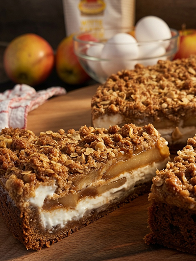 ambachtelijke Apple Crumble Cheesecake combineert een romige cheesecake met gekarameliseerde appel en een knapperige crumble topping.